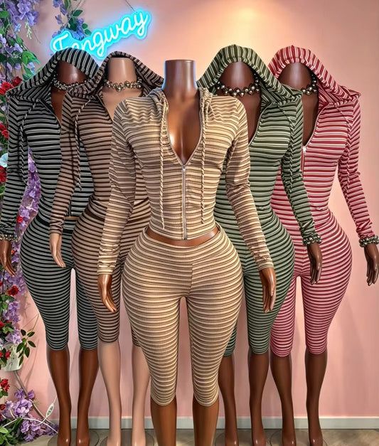 Four mannequins wearing matching striped hooded two-piece sets in different colors: black and gray, beige and brown, olive green and brown, and pink and brown. The center mannequin wears a beige and brown set with a front zipper. HBK HOOD BRAT KOLLECTION
